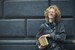 Young Man Leaning Against The Wall Holding A Books